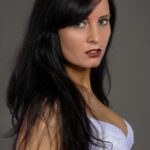 A striking portrait of a woman in lace lingerie against a gray backdrop.